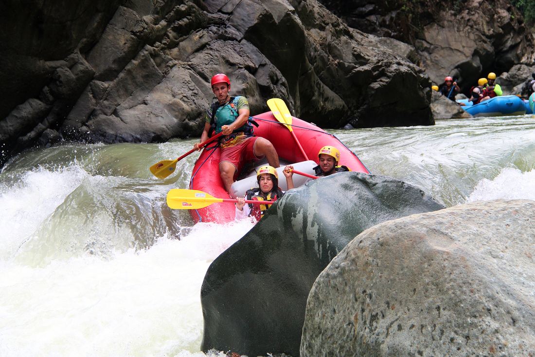 Raft sliding past a boulder in the Chorro canyon