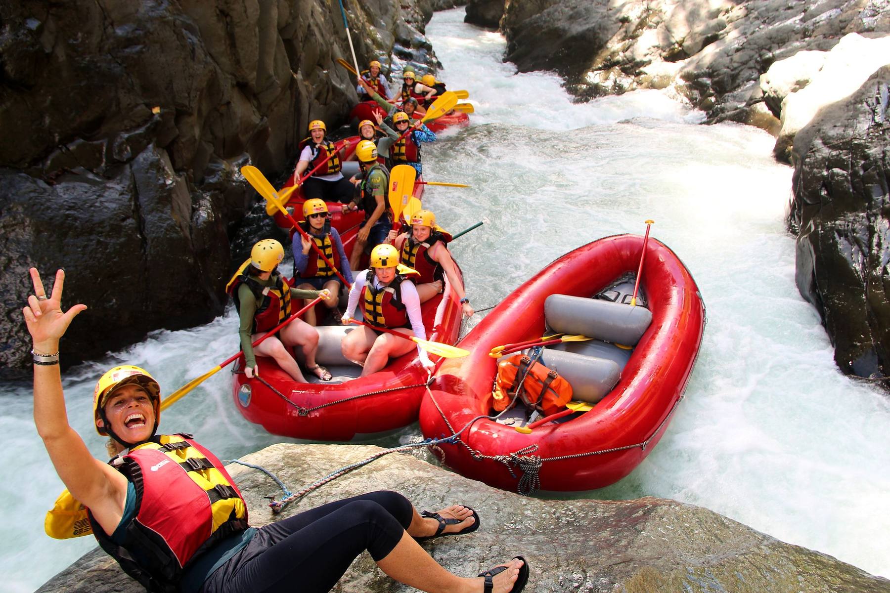 A guest waving from the rocks beside two rafts in the Chorro canyon