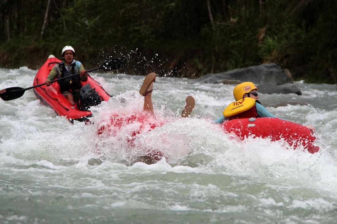 A tuber going through a wave beside the guide's kayak