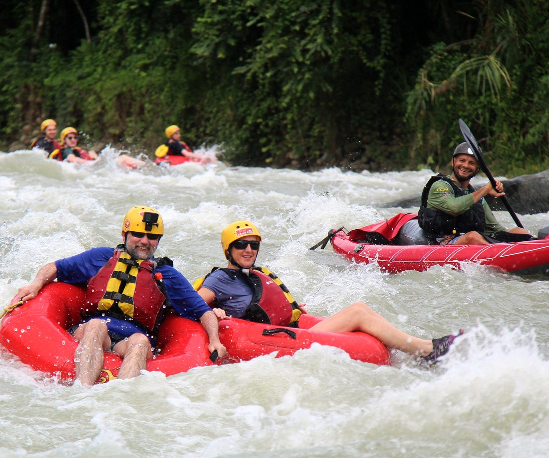 Two tubers in a rapid with the guide in a kayak