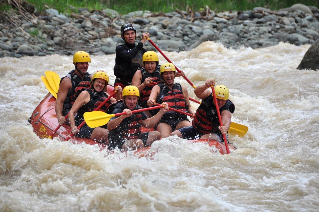 A full raft paddling through white water on the Naranjo