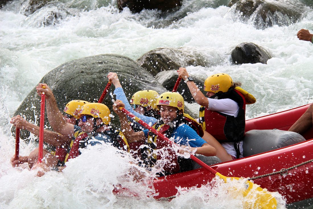 Paddlers hitting a rapid head on beside a boulder on the Naranjo