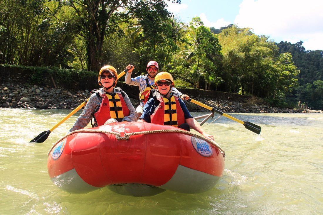 Guests smiling in the raft while the guide rows on the Savegre