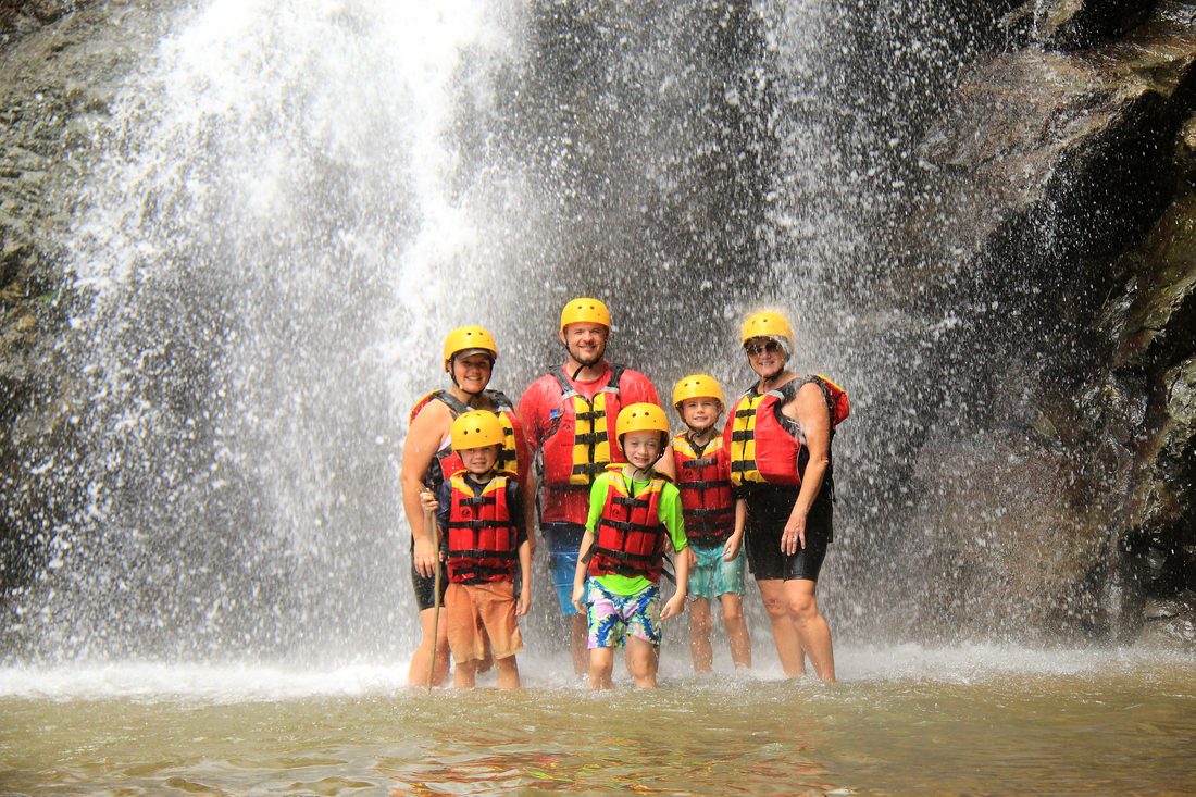 A family standing in front of a waterfall on the Savegre trip